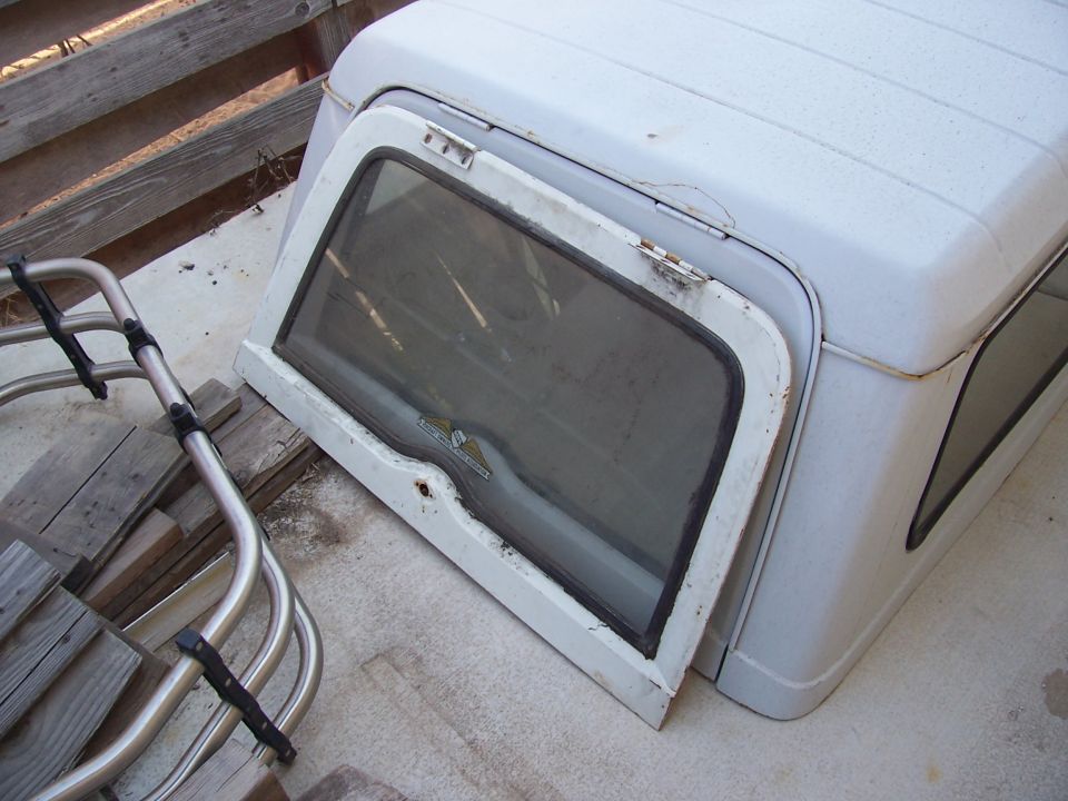 White Jeep hardtop with open side window, resting on wooden planks