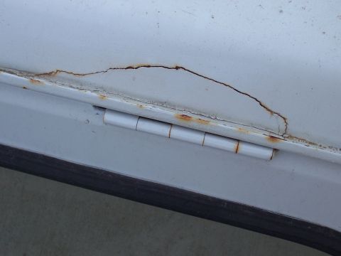 1970 Jeep Jeepster - Rust is forming around a door hinge, with paint cracking along the seam.
