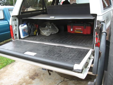 1994 Ford Bronco - The open tailgate of a pickup truck reveals a red toolbox and other items stored in the bed.