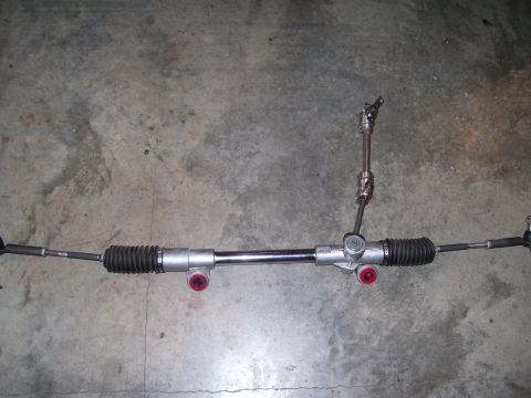 1990 Ford Mustang - A vehicle steering rack and pinion assembly is shown laid out on a concrete surface.