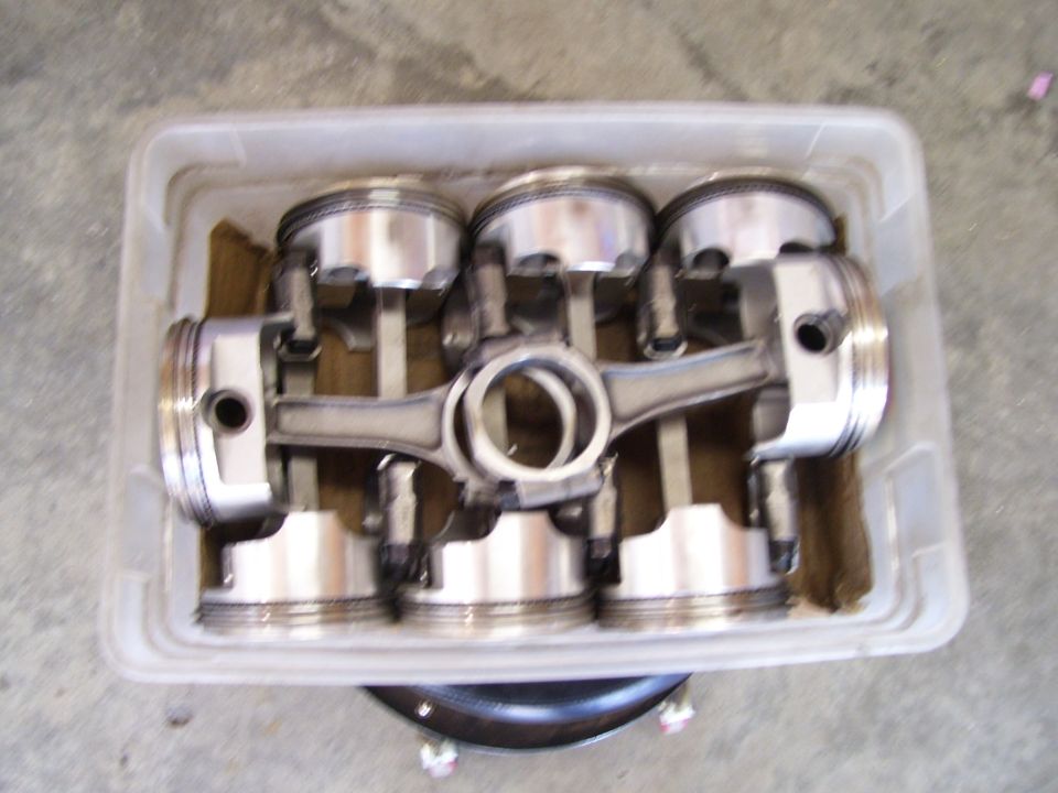 Set of four pistons and connecting rods in a plastic container