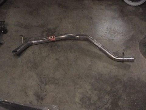 1991 Ford Bronco - A metal exhaust pipe lies on a concrete surface, showing some text on a sticker.