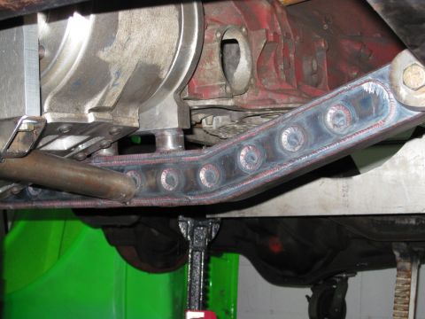 1995 Ford Bronco - Custom suspension arm with circular cutouts is visible underneath a vehicle, supported by a jack.