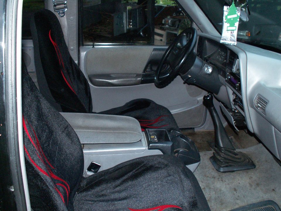 Truck interior with black seat covers red flames and a floor shifter