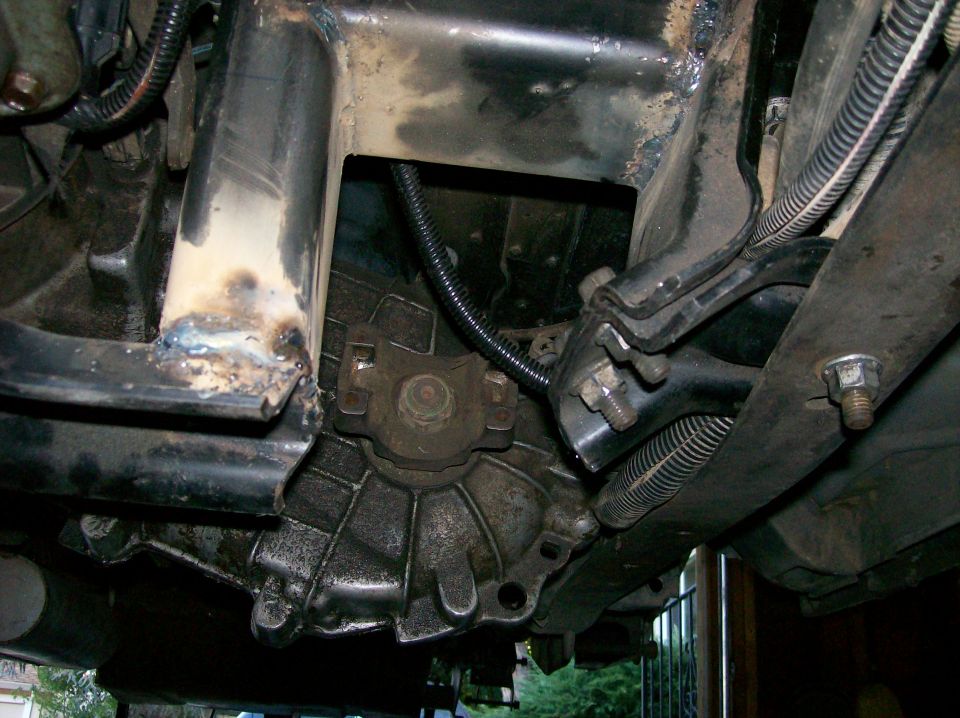 Underside view of vehicle's transmission and frame. Shows some welding on the frame