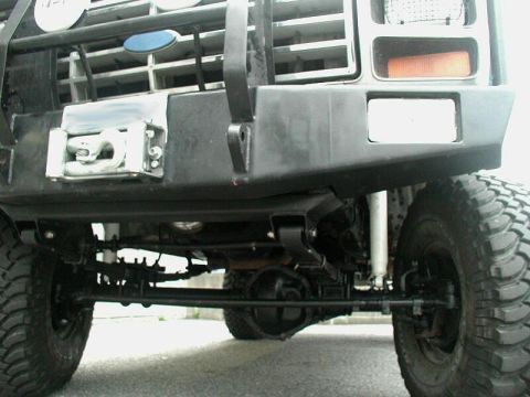 1985 Ford Bronco - Close-up of a modified Ford Bronco's front end, showing off-road modifications and suspension components.