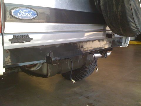 1995 Ford Bronco - The rear bumper area of a Ford Bronco is shown, the spare tire and visible exhaust components.