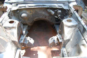 1964 Ford Fairlane - The engine bay of a 1964 Ford Fairlane shows signs of rust and is missing its engine.