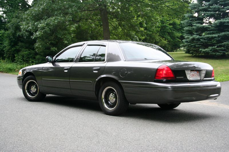 Grey Ford Crown Victoria sedan rear three-quarter view parked on a road