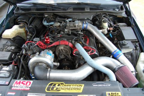 1985 Mercury Grand Marquis - Engine bay modified with a turbocharger system, prominent aftermarket parts and branding.