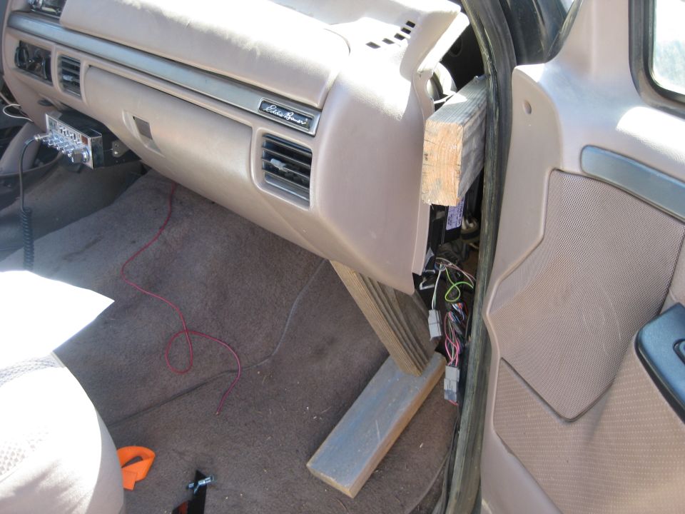 1995 Ford Bronco interior showing dashboard, glove box, and exposed wiring near the steering column, held by a wooden brace