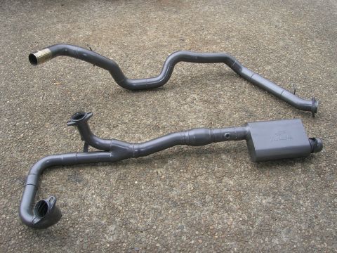 1996 Ford Bronco - Two sections of an exhaust system, including a muffler with the "Walker" brand name visible, are laid out on a concrete surface.