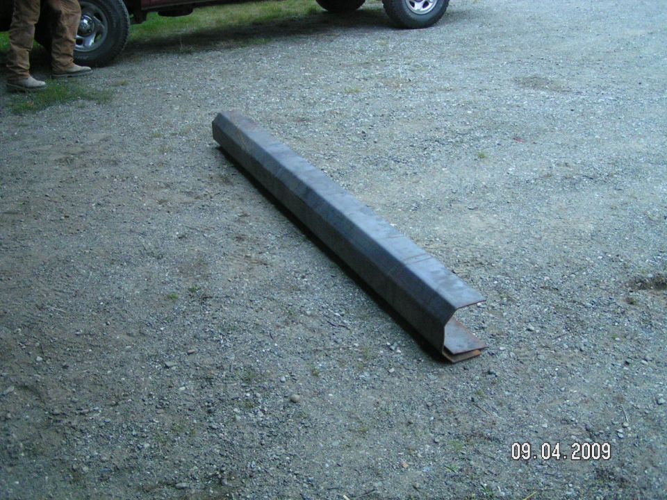 Long formed steel channel section lying on gravel beside a pickup, dated 2009