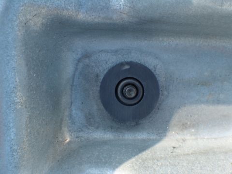 1996 Ford Bronco - A close-up view of a bolt head set within a gray, textured material, possibly part of a vehicle's undercarriage or interior.