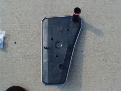 1996 Ford Bronco - A transmission filter is shown lying on a concrete surface next to a small plastic bag.