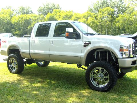 2007 Ford Mustang - This lifted white crew cab pickup truck is shown from a 3q front angle, large chrome wheels and a two-tone paint scheme.