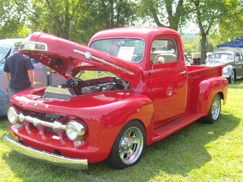 2007 Ford Mustang - A bright red 1951 Ford F-series pickup truck is displayed with its hood open, revealing the engine.
