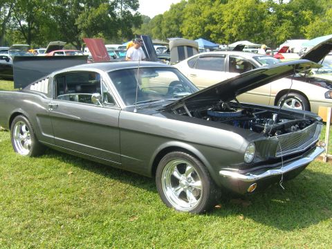 2007 Ford Mustang - A classic Mustang Fastback is displayed with its hood up at a car show, surrounded by other vehicles.