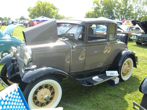 2007 Ford Mustang - A classic 1930 Ford Model A coupe is displayed at an outdoor event with other vehicles.