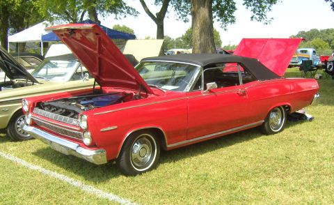 2007 Ford Mustang - A red convertible with its hood open is displayed on a grassy field with tents in the background.