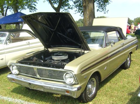 2007 Ford Mustang - A gold 1964 Ford Falcon convertible is displayed with its hood open, parked on grass next to another vehicle.
