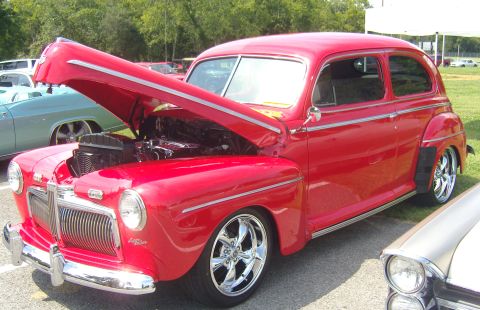 2007 Ford Mustang - Red 1946 Ford hot rod sedan with hood open, parked outdoors.