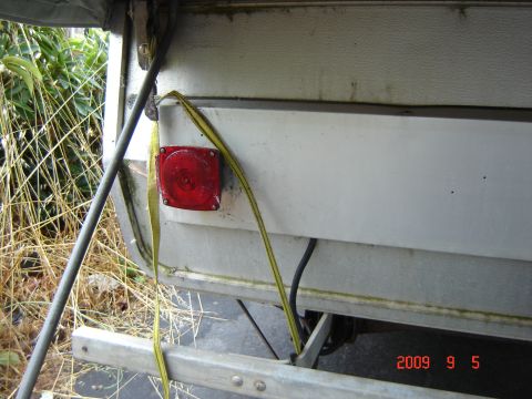 1993 Ford Bronco - Close-up of a pop-up tent trailer's rear, showing a red light and securing strap.
