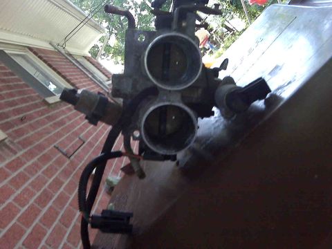 1995 Ford Bronco - This is a close-up view of a vehicle's throttle body assembly, showing its internal components and external connections.