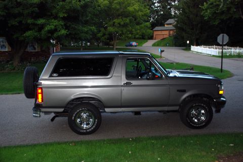 1995 Ford Bronco - A gray Ford Bronco is parked on the side of a road in a residential area.