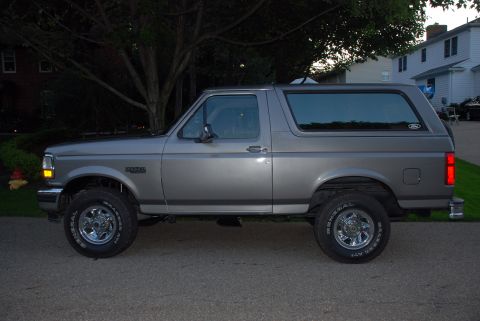 1995 Ford Bronco - This gray Ford Bronco is viewed from the side, showing its distinctive body style and chrome wheels.
