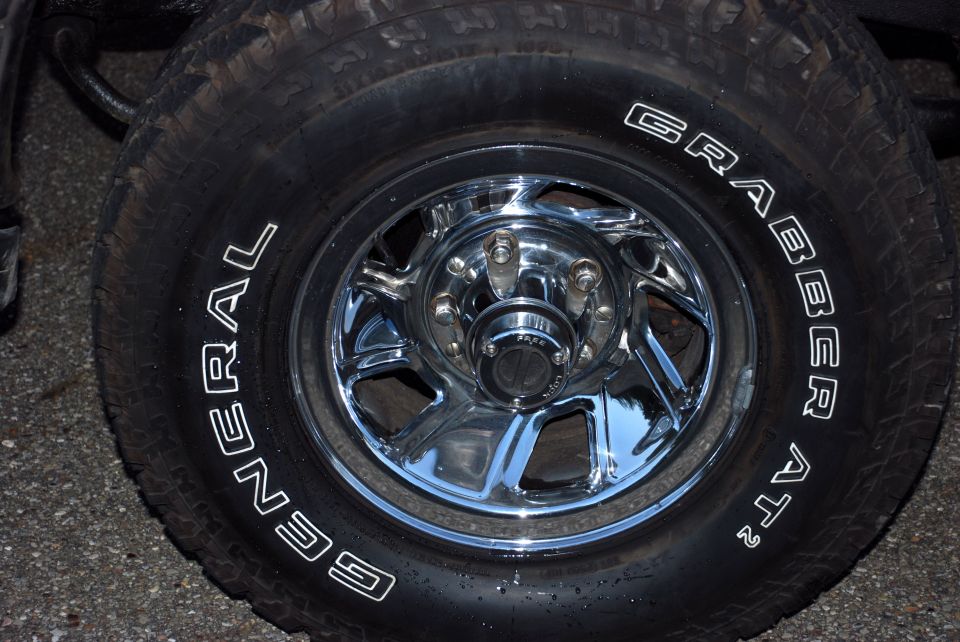 Chrome wheel with General Grabber AT2 tire. Center cap has text