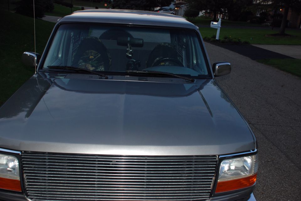 Gray Ford Bronco front view with chrome grille and camouflage seat covers visible through the windshield