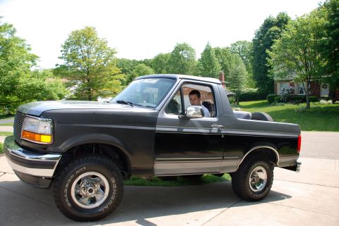 1995 Ford Bronco - This 1995 Ford Bronco features a two-tone gray and black paint scheme and is parked on a residential driveway.