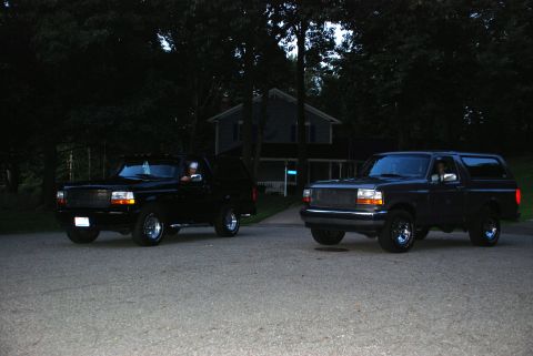 1995 Ford Bronco - Two Ford Broncos are seen parked in front of a house at dusk.