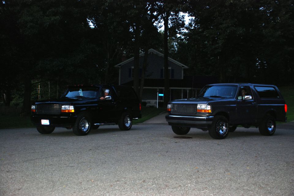 Two black Ford Broncos parked on a driveway, one in front of the other