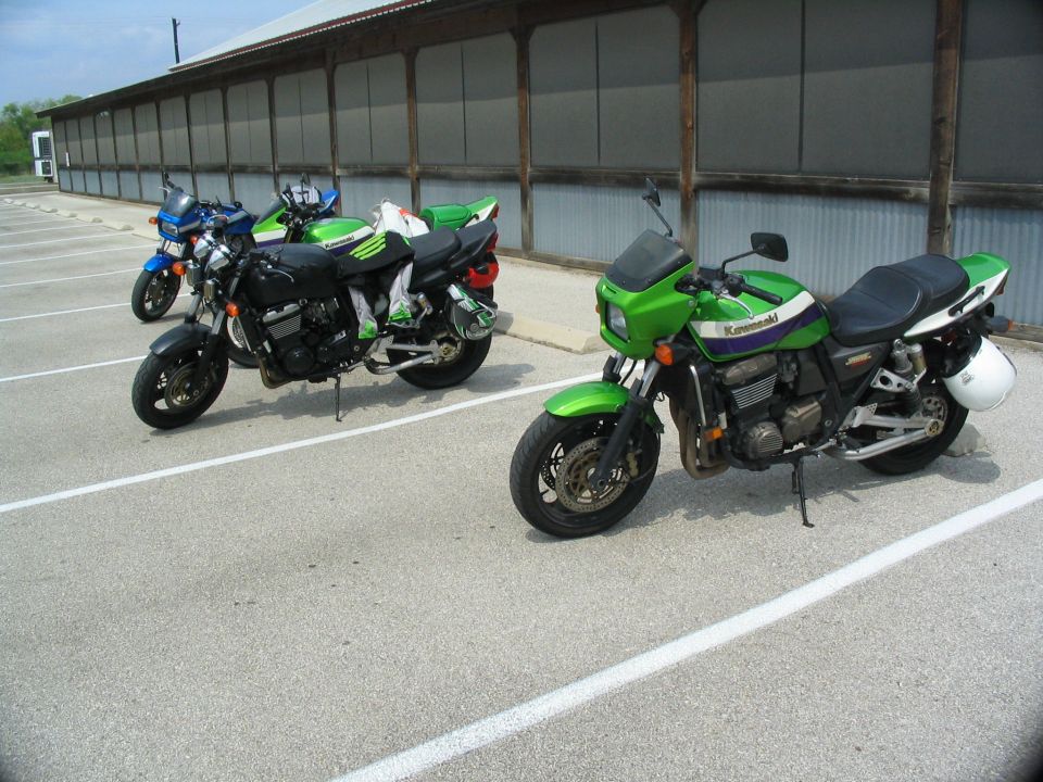 Green Kawasaki motorcycle parked in lot with two other bikes nearby
