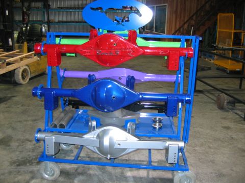 1992 Ford Mustang - Several painted rear axle assemblies are displayed on a blue metal cart in a workshop.