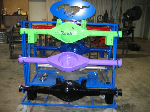 1992 Ford Mustang - Multiple painted rear axle assemblies are displayed on a rolling cart in a workshop setting.