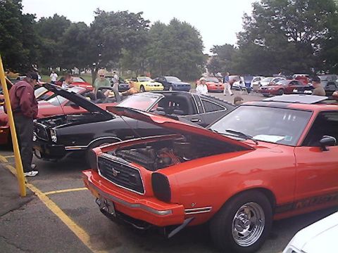 1978 Ford Mustang II - Two Ford Mustang IIs, one red and one black, are displayed with their hoods open at an outdoor car show.