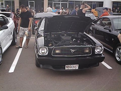 1978 Ford Mustang II - A black 1978 Ford Mustang II is displayed with its hood open, parked among other vehicles at an outdoor event.