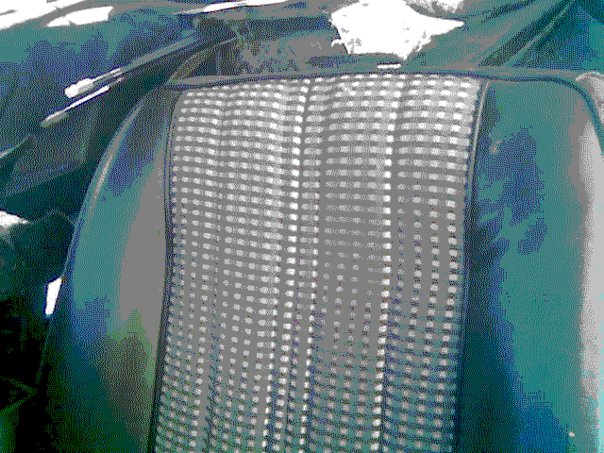 Close-up of car seat fabric with a checkered pattern and dark green vinyl bolsters. Supermotors logo visible