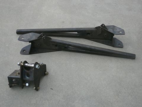1988 Ford Bronco - Set of suspension control arms and a mounting bracket on a concrete surface.