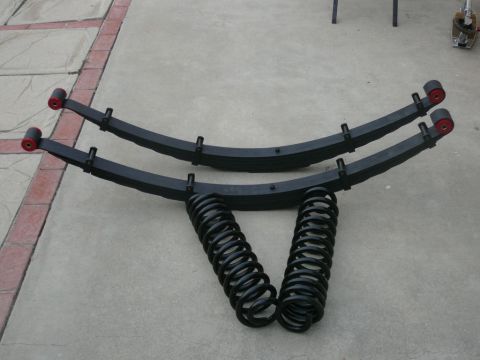 1988 Ford Bronco - A set of suspension parts, including leaf springs and coil springs, are displayed on a paved surface.