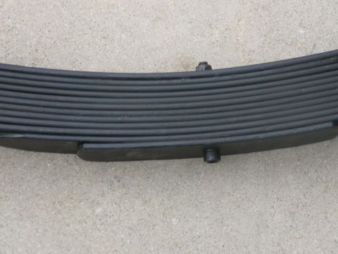 1988 Ford Bronco - A close-up view of a vehicle's leaf spring, showing its layered construction and bolted assembly.