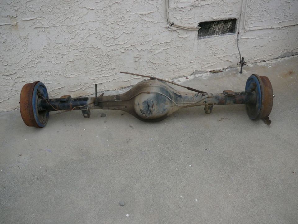 Rear axle assembly with drum brakes, showing rust on the drums