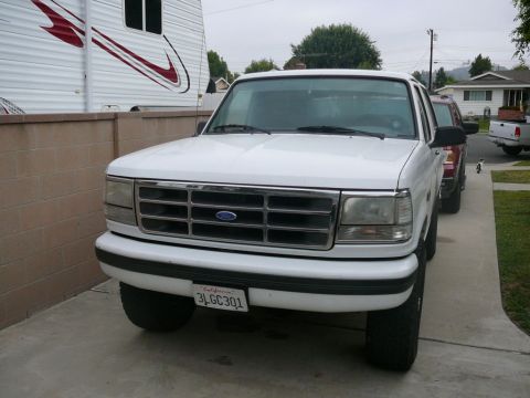1988 Ford Bronco - A white Ford pickup truck is parked in a driveway next to a trailer and another vehicle.