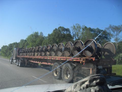 1988 Ford Bronco - A semi-truck transports a large quantity of train wheels on its flatbed trailer.