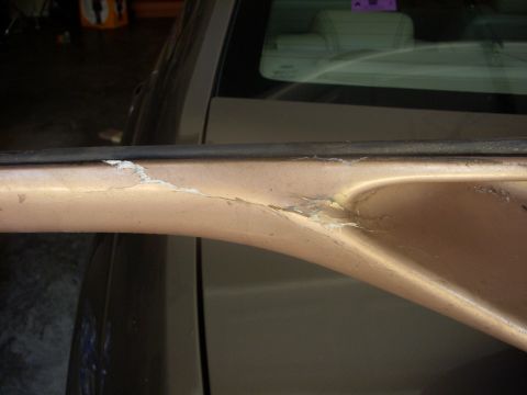 1993 Ford Bronco - Damaged car door trim shows peeling paint and underlying material.