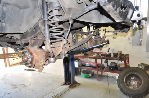 1996 Ford Bronco - Close-up view of a vehicle's front suspension system being worked on while elevated on a lift.