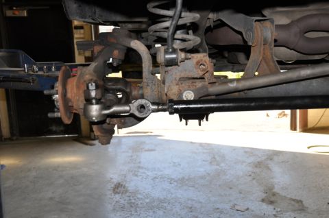 1996 Ford Bronco - Undercarriage view of worn steering and suspension components on a vehicle.